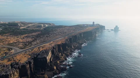 Aerial view of Cabo Carvoeiro cliffs with road, lighthouse, rugged shoreline Stock Footage 321979802