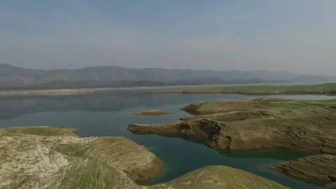 Aerial view of a calm lake with rolling hills and distant mountains Stockbeeldmateriaal 335270701