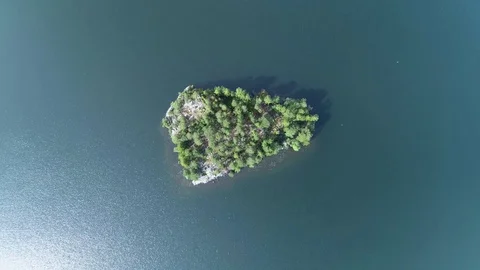 Aerial view camera moves down descending above green forest island filming down Stock Footage 78796792