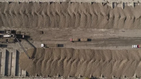 Aerial view. Camera pans along line of trucks with sugar beet trailers. Video stock 251673187