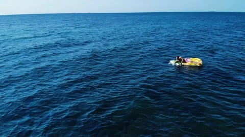 Aerial view camera pans around guy in pink swimming trunks, who lies on Stock Footage 138608339