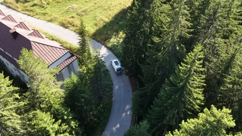 Aerial View of Camper Van Driving Past Alpine Building on Mountain Road 库存影片 343927590
