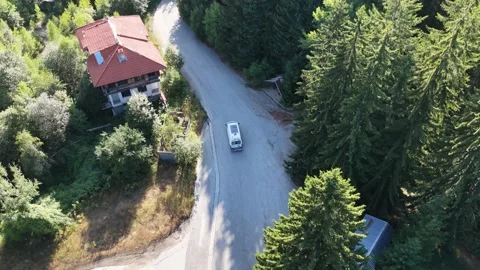 Aerial View of Camper Van Driving Along Mountain Road Past Houses 動画素材 343927836