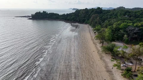 Aerial view captures calm ocean waves lapping sandy shore Stock Footage 332591087