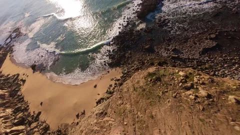 Aerial view captures dramatic cliffs, golden sand, and sparkling sea Video stock 344562387