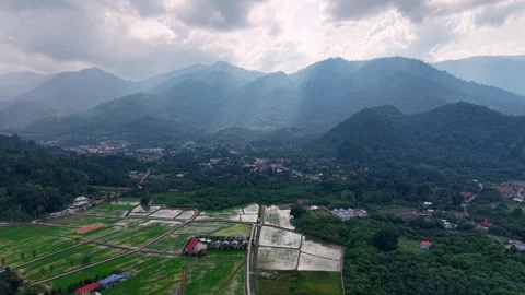 Aerial view captures mountains, clouds, and sunbeams piercing through Vídeos de archivo 344822143