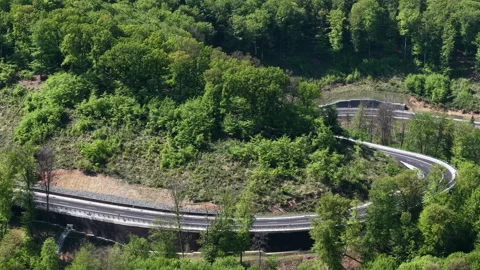 An aerial view captures a newly constructed highway winding through a dense Stock Footage 334137940