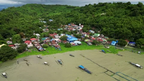 Aerial view captures a riverside town with boats, stilt houses, and lush Stock Footage 320074211