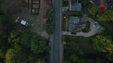 An aerial view captures a road lined with trees, homes, and a construction .. Stock Footage 340459338