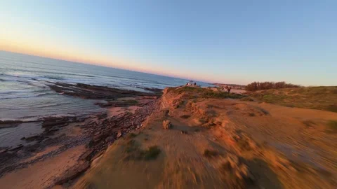 Aerial view captures serene ocean meeting rugged shore at sunset Stock Footage 344563439