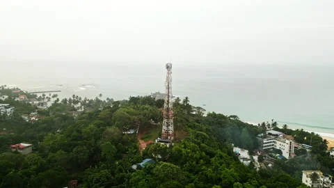 Aerial view captures towering communications mast rising above lush island Stock Footage 262068471