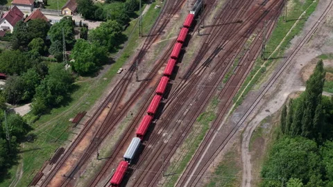 An aerial view captures a vibrant red freight train moving along railway tracks Stock Footage 337470345