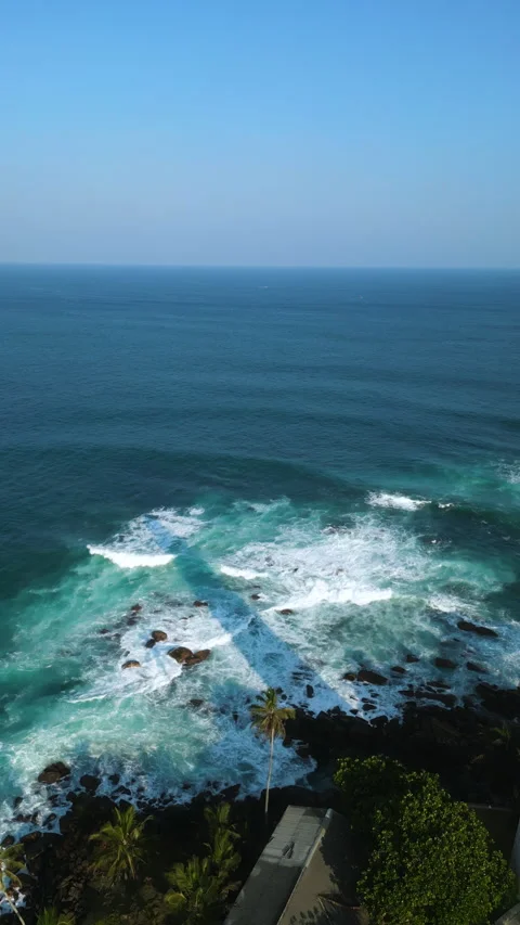 Aerial view captures waves crashing against tropical coastline with historic Stock Footage 270423697