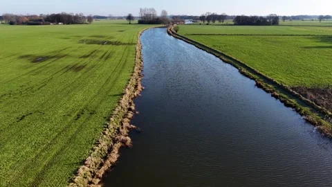 An aerial view captures a wide river or canal stretching through vibrant 库存影片 335727957