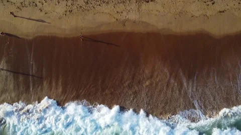 Aerial view capturing the mesmerizing meeting of sandy beach and ocean waves Stock Footage 317658685
