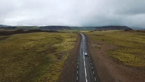 Aerial view of car driving on asphalt road in Iceland, follow from rear by drone Stock Footage 98123772