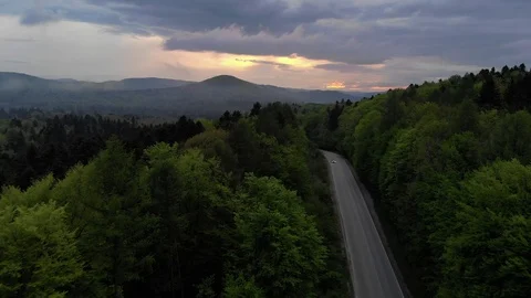 Aerial view of  car driving on country road in forest. Cinematic drone shot  Stock Footage