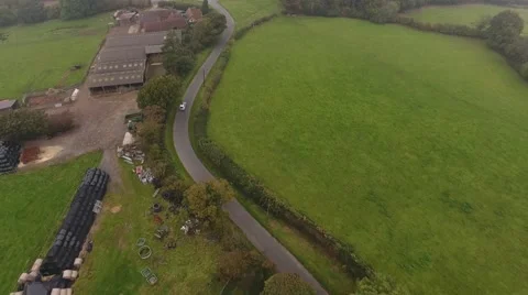 Aerial view of a car driving down a country lane past a farm. 動画素材 68698121