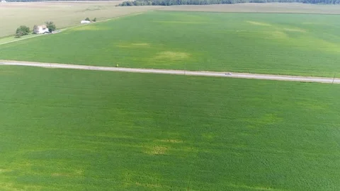 Aerial View of a Car Driving Down a Lone Country Road Surrounded by Farms Stock Footage 141017725