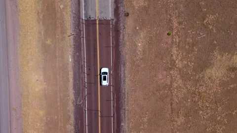 Aerial View of a Car Driving on an Open Road that Winds Through a Vast Arid Stock Footage 315317062