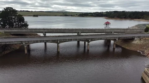 Aerial view of a car driving over a concrete bridge spanning a reservoir 스톡 동영상 340381735