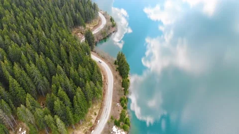 Aerial view of car driving through the mountain forest and the lake on the side Stock Footage 150664409
