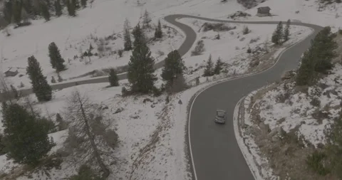 Aerial View of Car Driving Through Snowy Alpine Mountain Switchback Road in 스톡 동영상 332227124