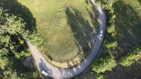 Aerial view of a car going in a turning countryside road Stock Footage 137916497