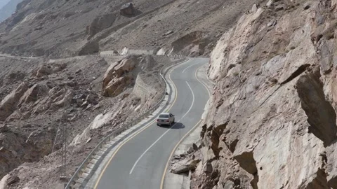 Aerial view of a car navigating a winding mountain road in Pakistan Stock Footage 314456326