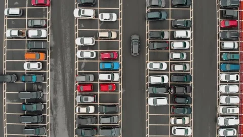 Aerial view of a car pulling out of a mall parking lot with many colorful cars Stockbeeldmateriaal 244858111