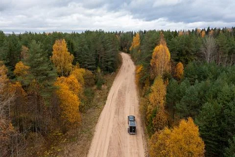 Aerial view of a car pulling a trailer driving along a winding sandy dirt road Stock Photos