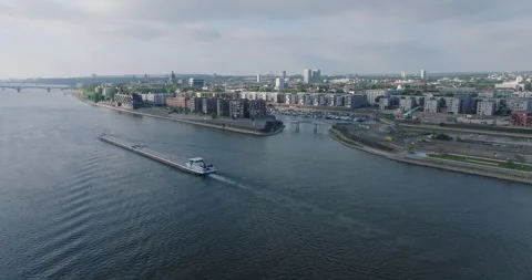 Aerial view of a cargo barge navigating a river through a modern city harbor Stockbeeldmateriaal 330064764