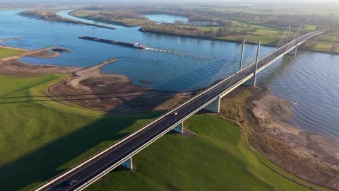 Aerial view of a cargo barge navigating under a modern cable-stayed bridge. Stock Footage 330718020