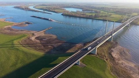Aerial view of a cargo barge navigating under a modern cable stayed bridge Stockbeeldmateriaal 331281602