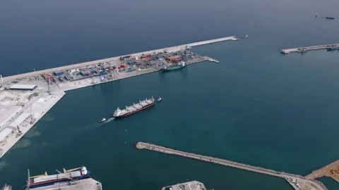 Aerial View of Cargo Ship Assisted by Tugboat in Port Stock Footage 344529062