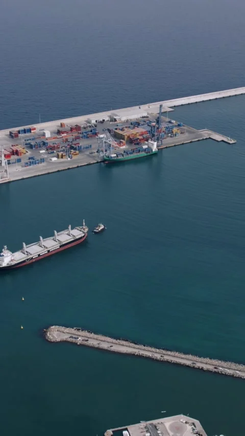 Aerial View of Cargo Ship Assisted by Tugboat in Port Stock Footage 345825132