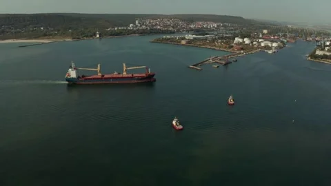 Aerial view of cargo ship calling at the port . Tugboats guiding the ship to the Stock Footage 154467416