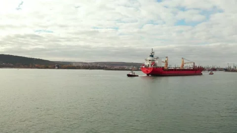 Aerial view of cargo ship calling at the port . Tugboats guiding the ship to the Stock Footage 154467597