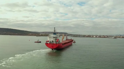 Aerial view of cargo ship calling at the port . Tugboats guiding the ship to the Video stock 154467880