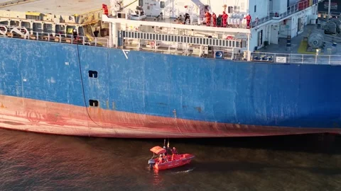 Aerial View of Cargo Ship Crew in Small Skiff Boat Making Repairs to Ship Stock Footage 304565910