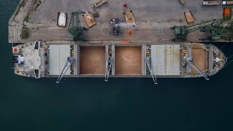 Aerial view of a cargo ship in a harbor uploading grains in a busy port during Stock Footage 285537741