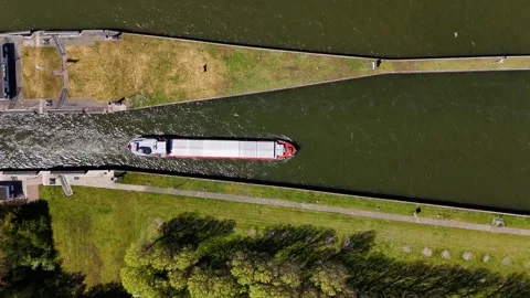Aerial view of a cargo ship navigating through a river canal lock 库存影片 335064095
