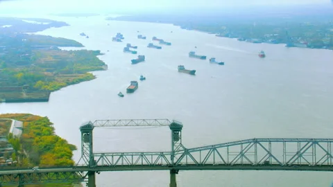 Aerial view of cargo ships sailing a river under a lift bridge Stock Footage 337018622