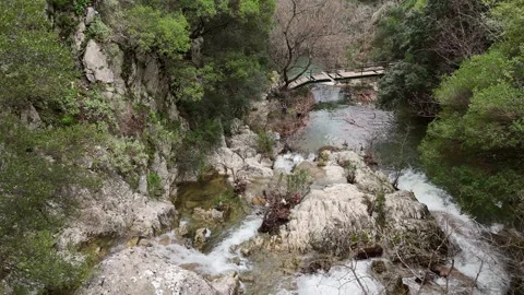 Aerial View of cascade rushes down the rocky cliffs near Polylimnio Waterfall in Video stock 303189063