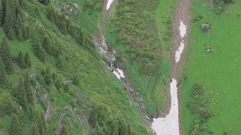 Aerial view of cascading waterfall flowing through green mountainous terrain Stock-Footage 340394167