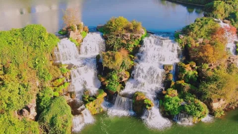 Aerial view of a cascading waterfall flowing into a calm pond in nature Stock Footage 342091960