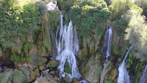 Aerial view of cascading waterfall over rocky forest cliff Stock Footage 324712009