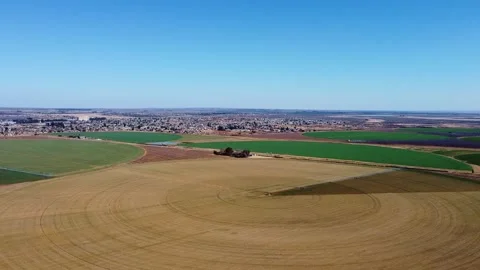 Aerial view of circular agricultural fields with a town in the distance under a Stock Footage 308952000