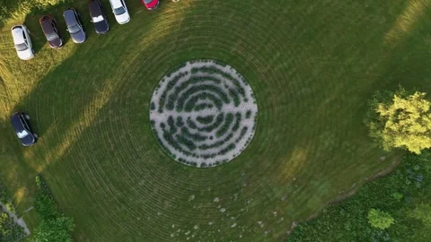 Aerial View of Circular Labyrinth Garden and Parked Cars in Lush Green Field Stock Footage 338165378
