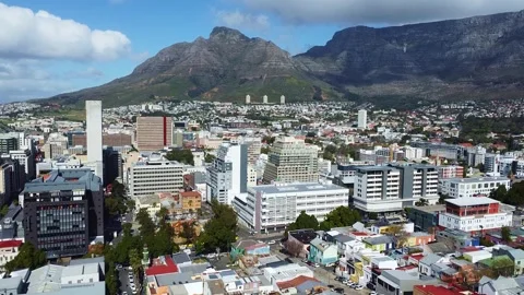 Aerial view of cityscape with table mountain in background on a partly cloudy Stock Footage 308976997